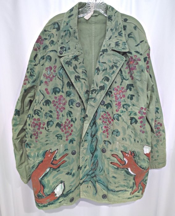 The front of a green jacket with foxes and grapes painted on it.