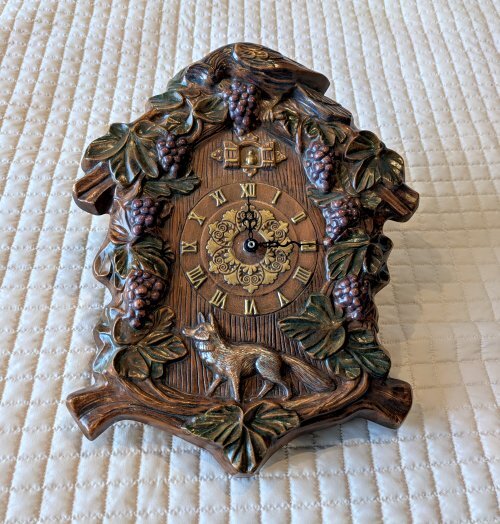 Large clock with a fox at the bottom and grapes lining the top.