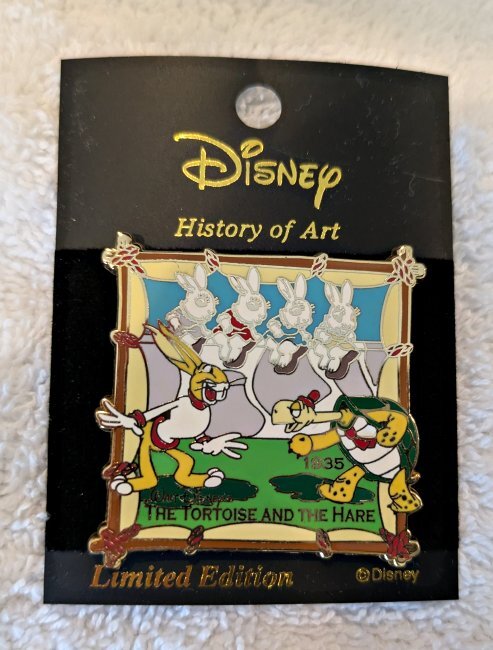 Square pin with a tortoise and hare on it.