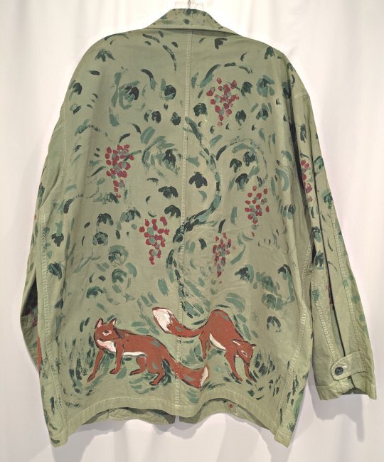 The back of a green jacket with foxes and grapes on it.