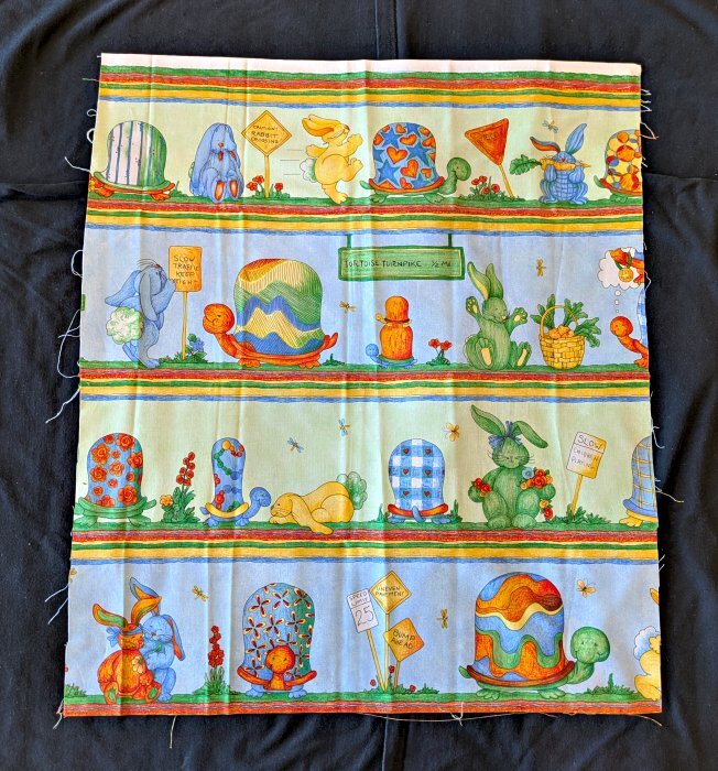 A segment of cut cloth with colorful tortoises and hares.